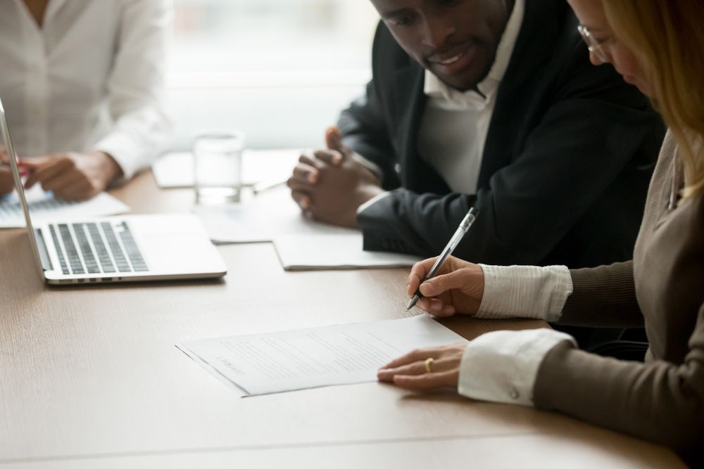 A Man And A Woman Are Sitting At A Table Talking To Each Other — Loretta Davison Financial Solutions In Wollongong, NSW 