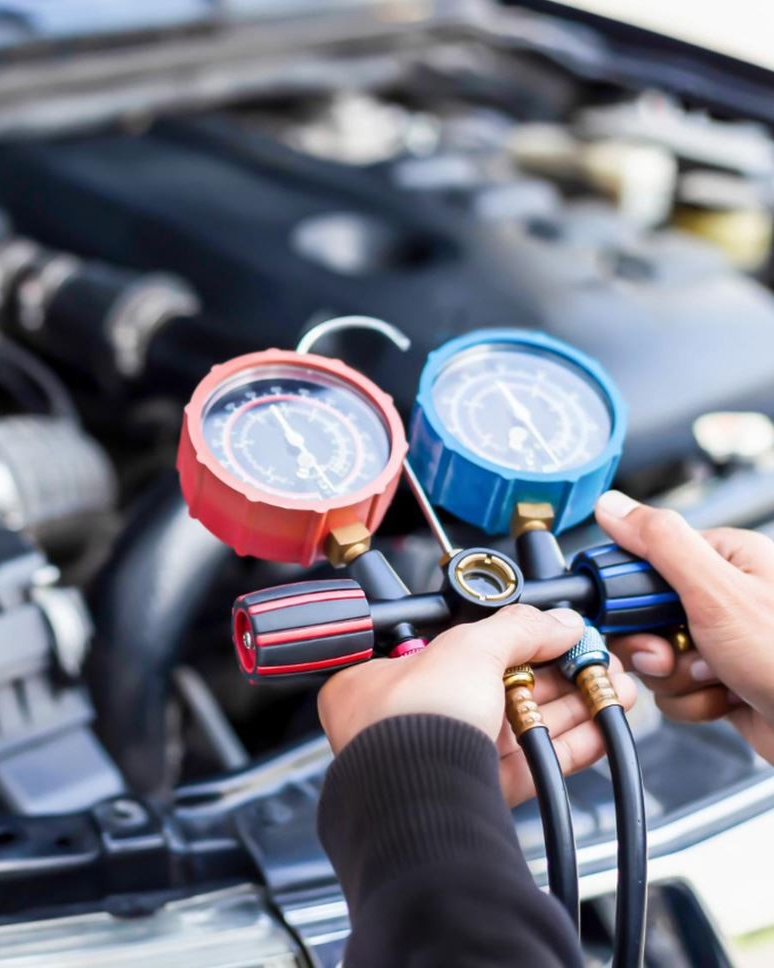 Hands connecting gauges to a car engine. Red and blue gauges, black hoses.