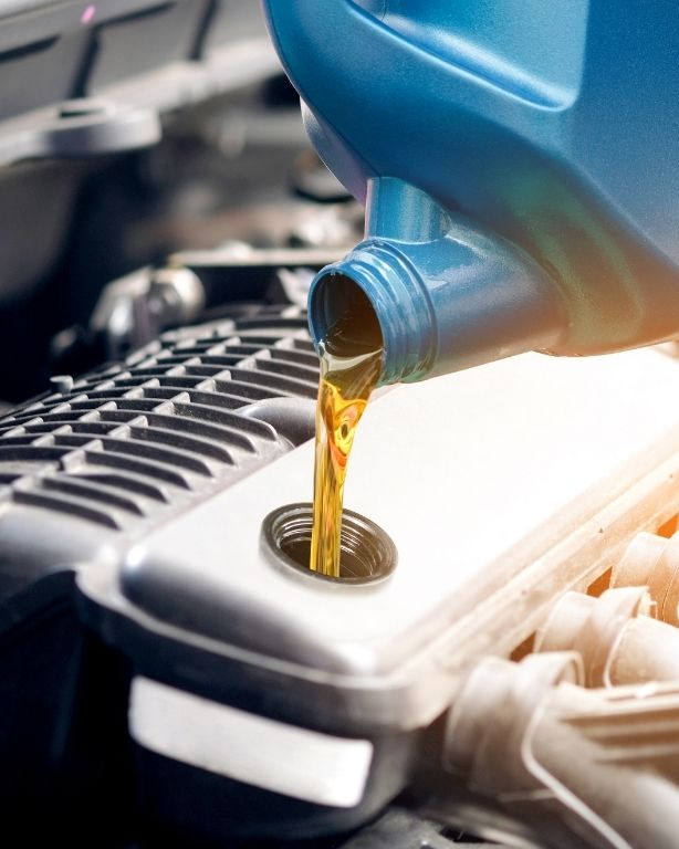 Pouring oil from a blue container into a car engine, highlighting maintenance.