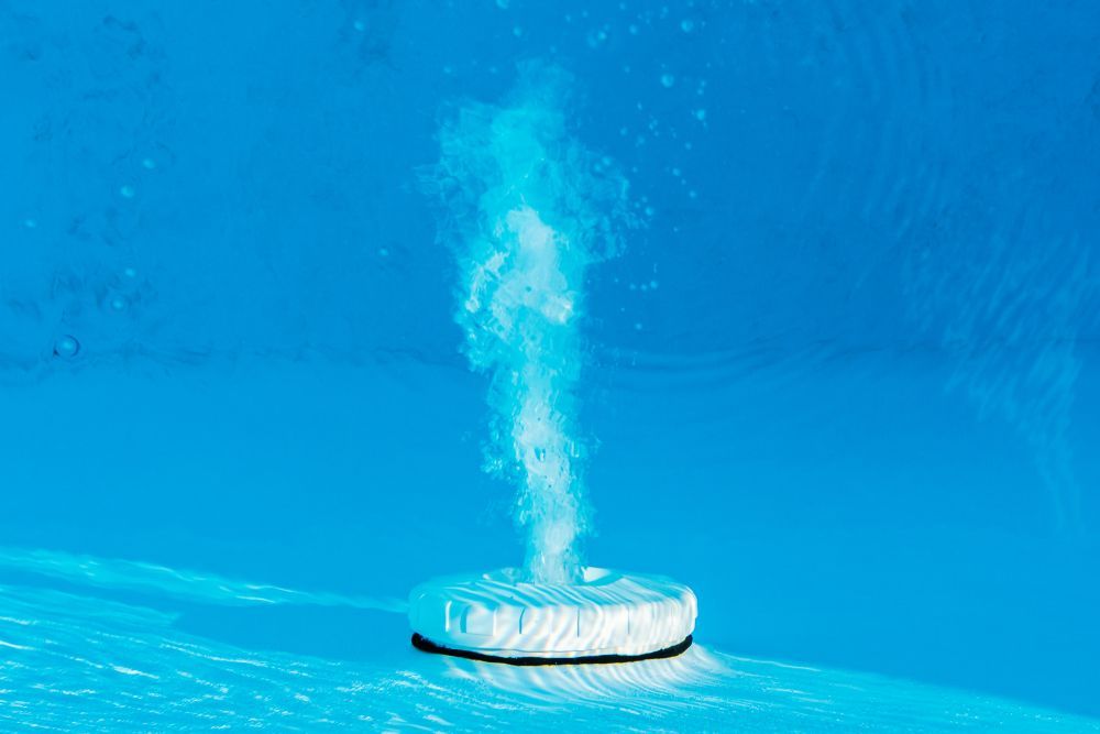 A White Object Is Floating in A Swimming Pool with Bubbles Coming out Of It — Whitsunday Pool Service in Cannonvale, QLD