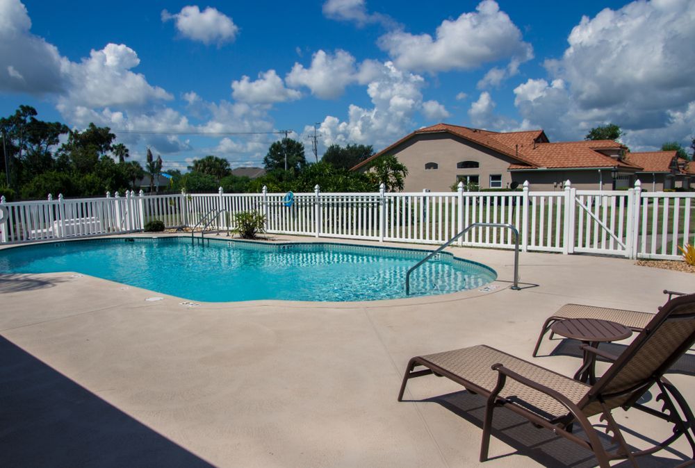 A Large Swimming Pool Surrounded by Chairs and A White Fence —
Whitsunday Pool Service in Cannonvale, QLD 