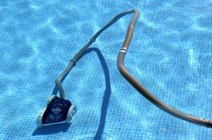 A Robotic Vacuum Cleaner is Attached to a Hose in a Swimming Pool — Whitsunday Pool Service in Cannonvale, QLD