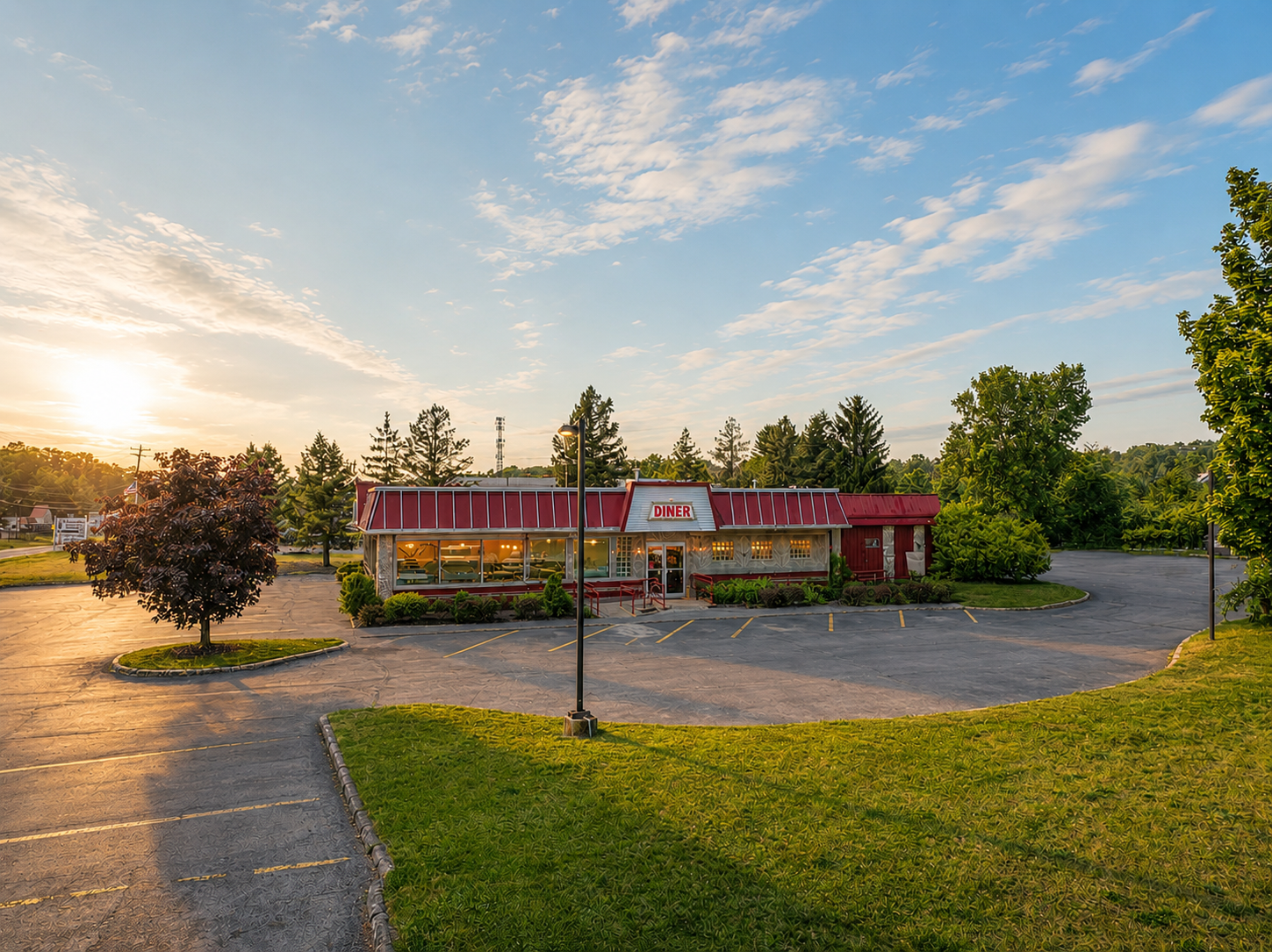 Sunlit roadside diner with red awning, picnic tables, and empty parking lot at sunset