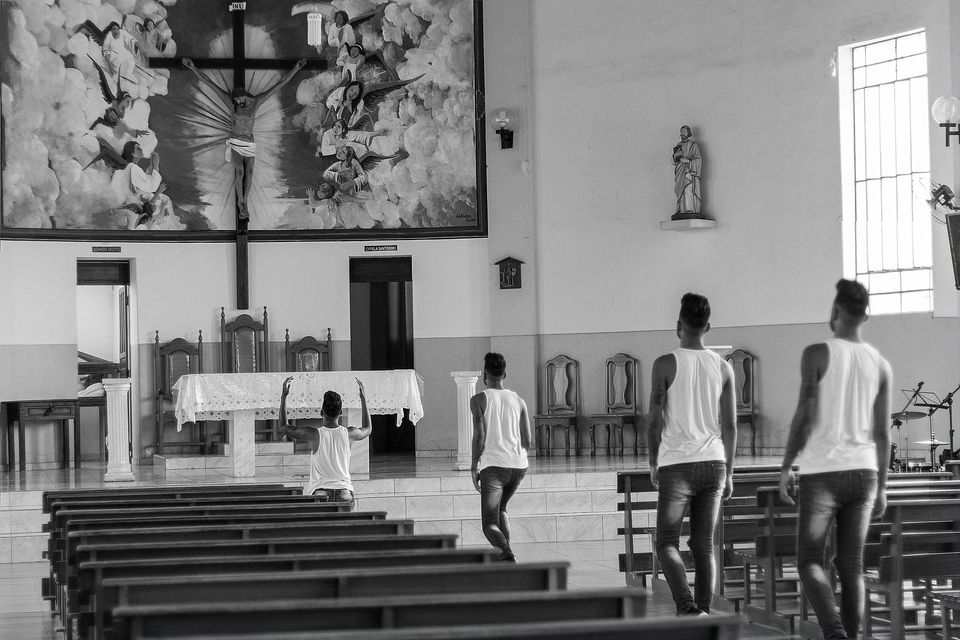 People walking down a church aisle toward the altar in a black-and-white interior.