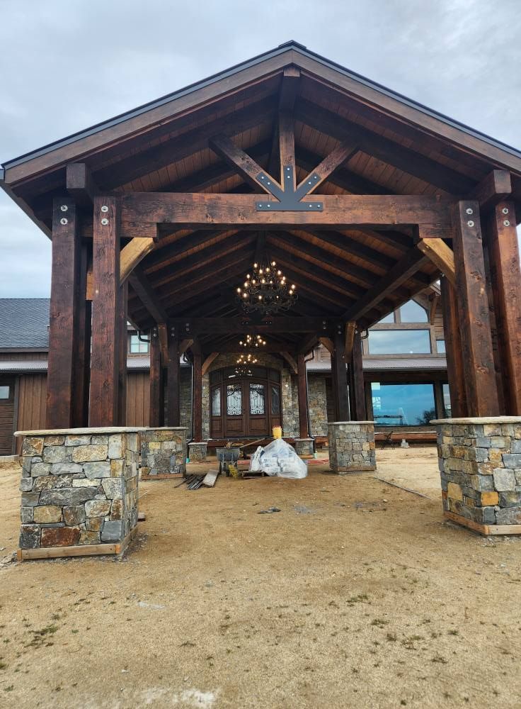 Wooden covered entrance with stone pillars and hanging lights over a gravel walkway