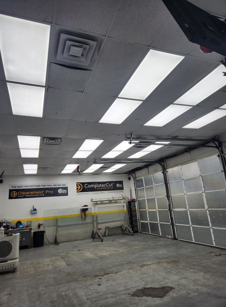 Empty auto shop interior with fluorescent lights, concrete floor, and garage door