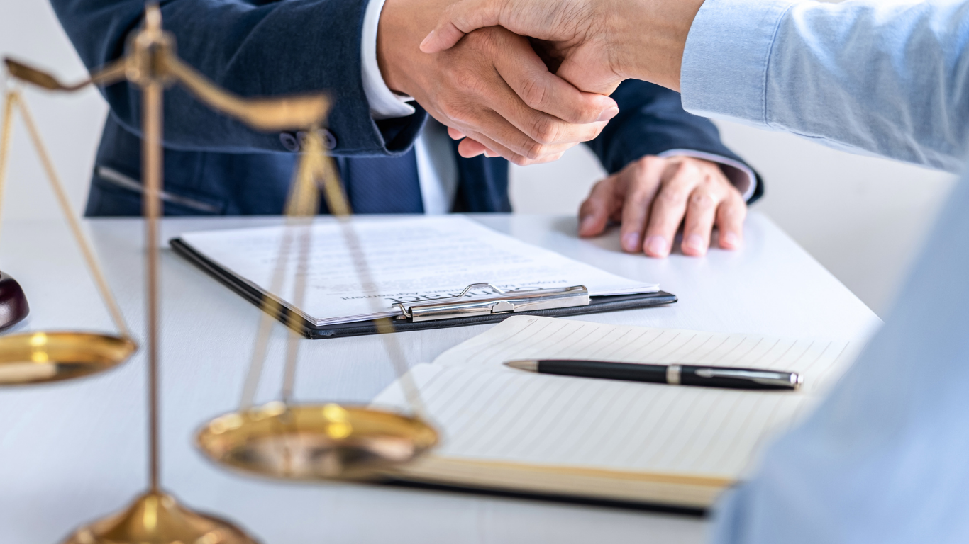 Businesspeople shaking hands at a table, two men and a woman, office setting.