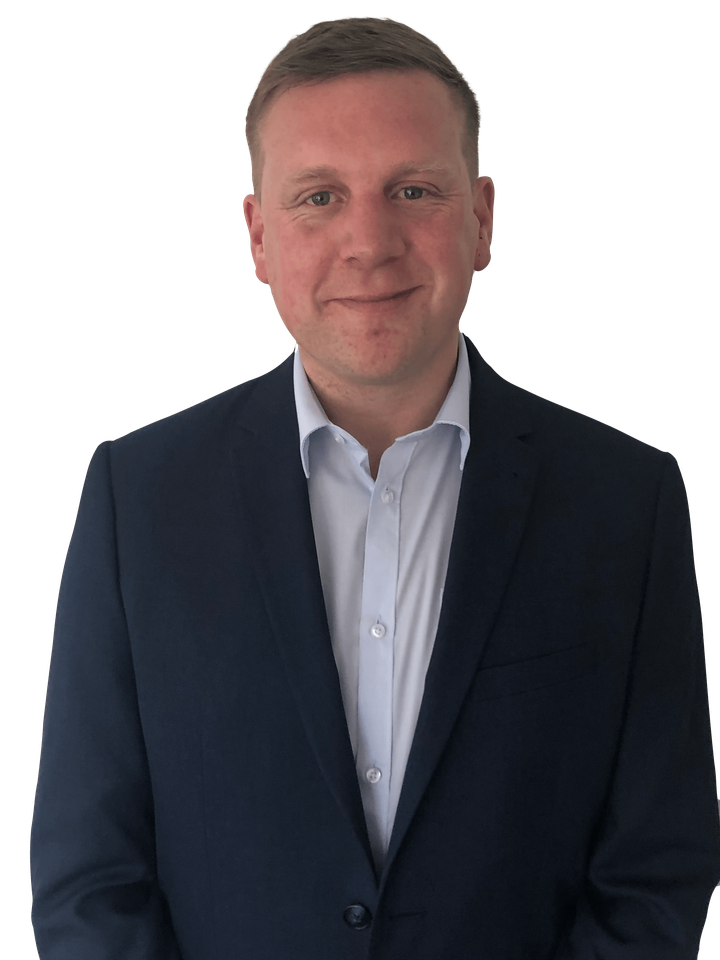 A man in a suit and white shirt is standing in front of a white background.