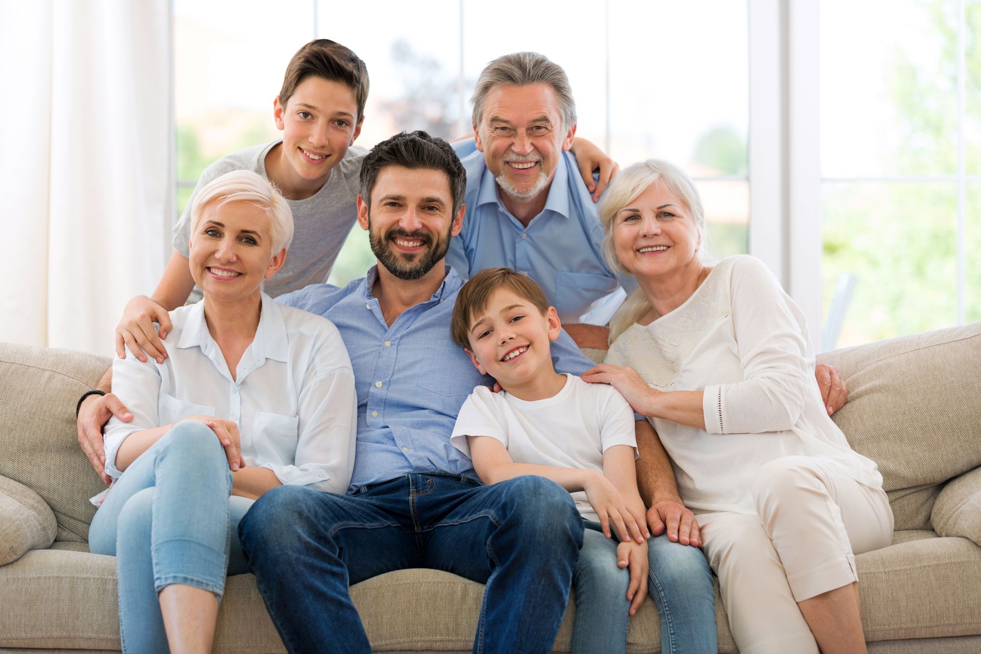 A large family is posing for a picture while sitting on a couch.