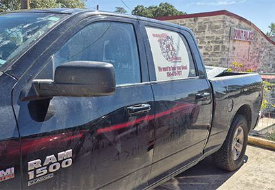 Black Ram 1500 pickup truck parked beside a stone building under a blue sky