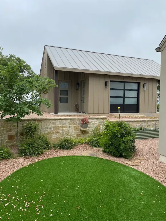 Modern house exterior with metal roof, brick planter, and landscaped front yard