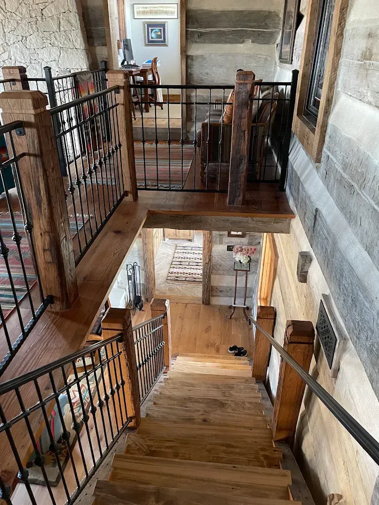 Stone stairwell with wooden steps and black iron railings in a historic interior.