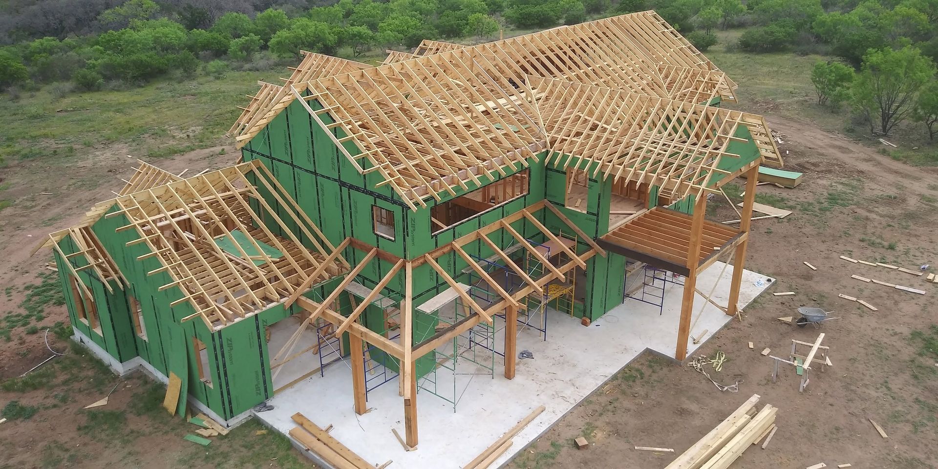 Partially built green house with exposed wooden roof trusses on a construction site