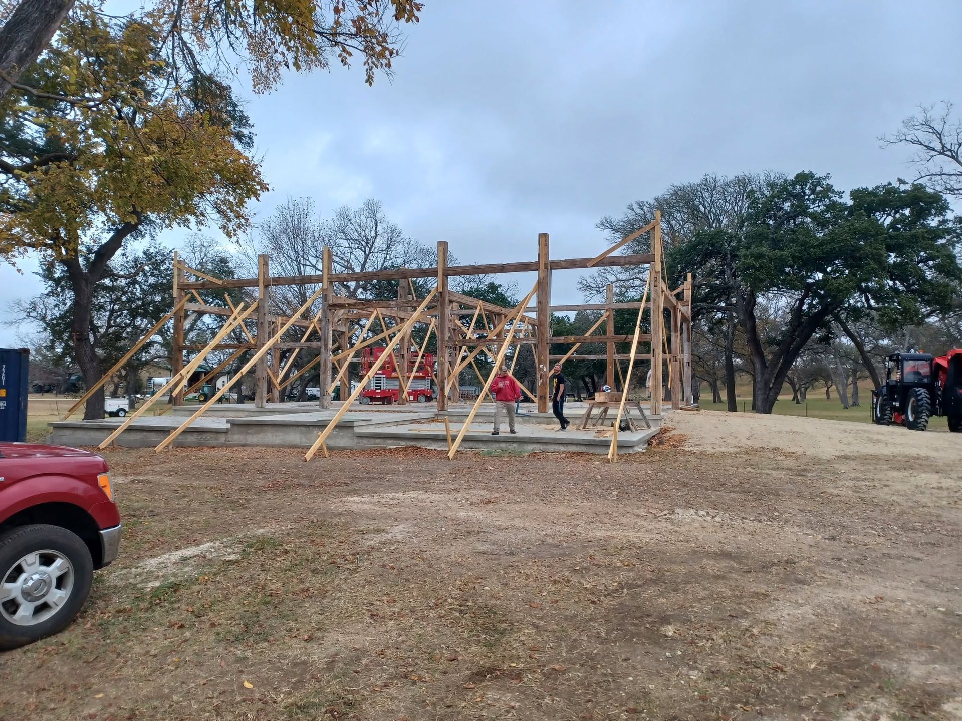 People climbing a wooden obstacle course outdoors on a cloudy day