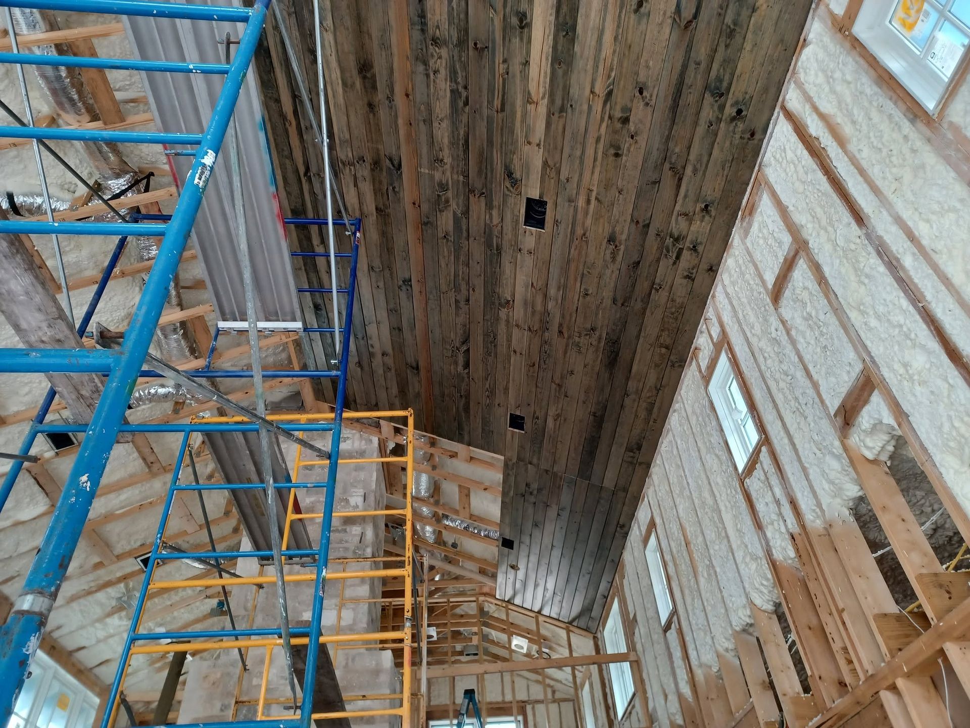 Scaffolding inside a large building with a high wooden ceiling and tall windows