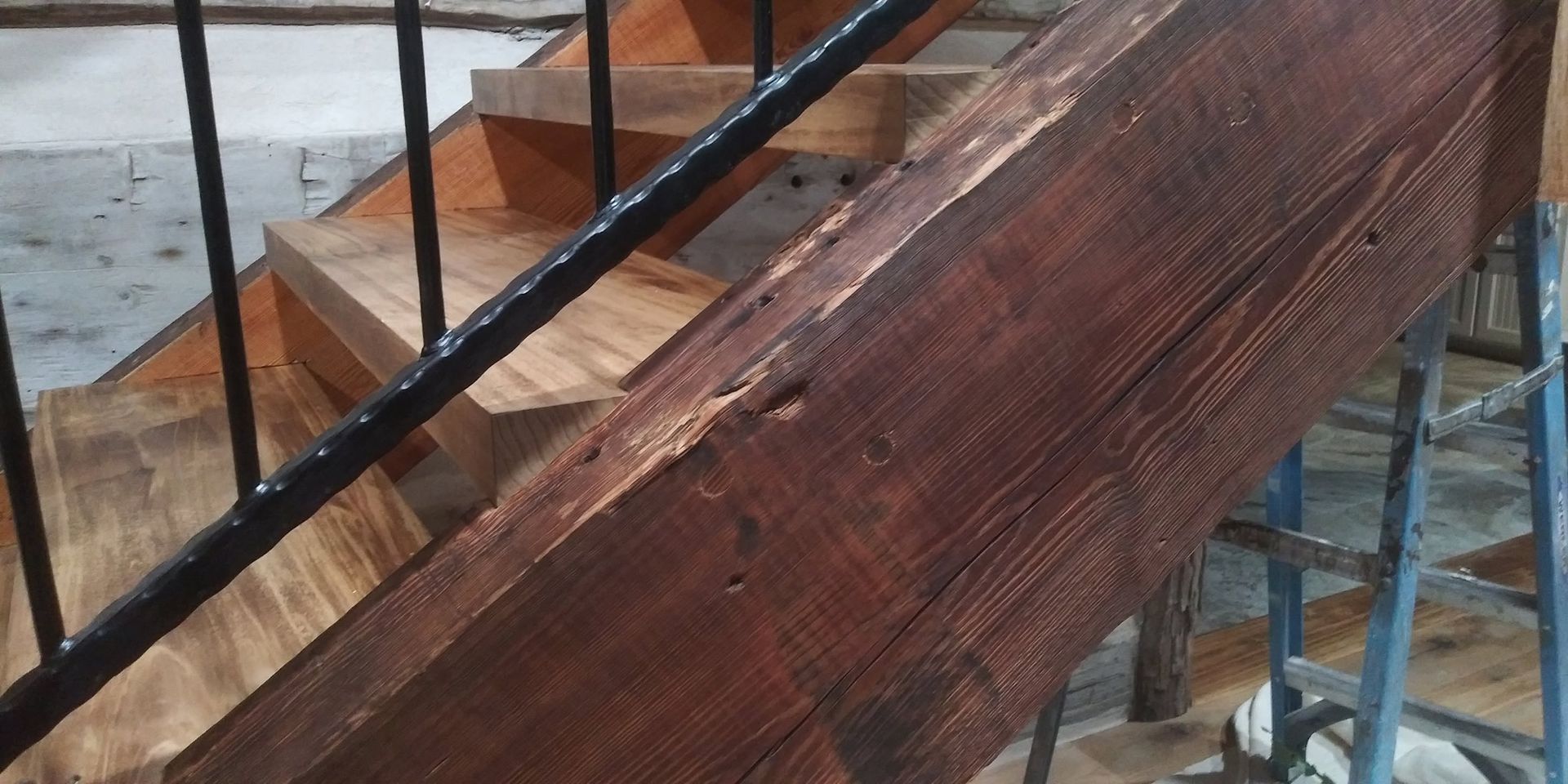 Wooden staircase with black railings beside a snowy outdoor scene