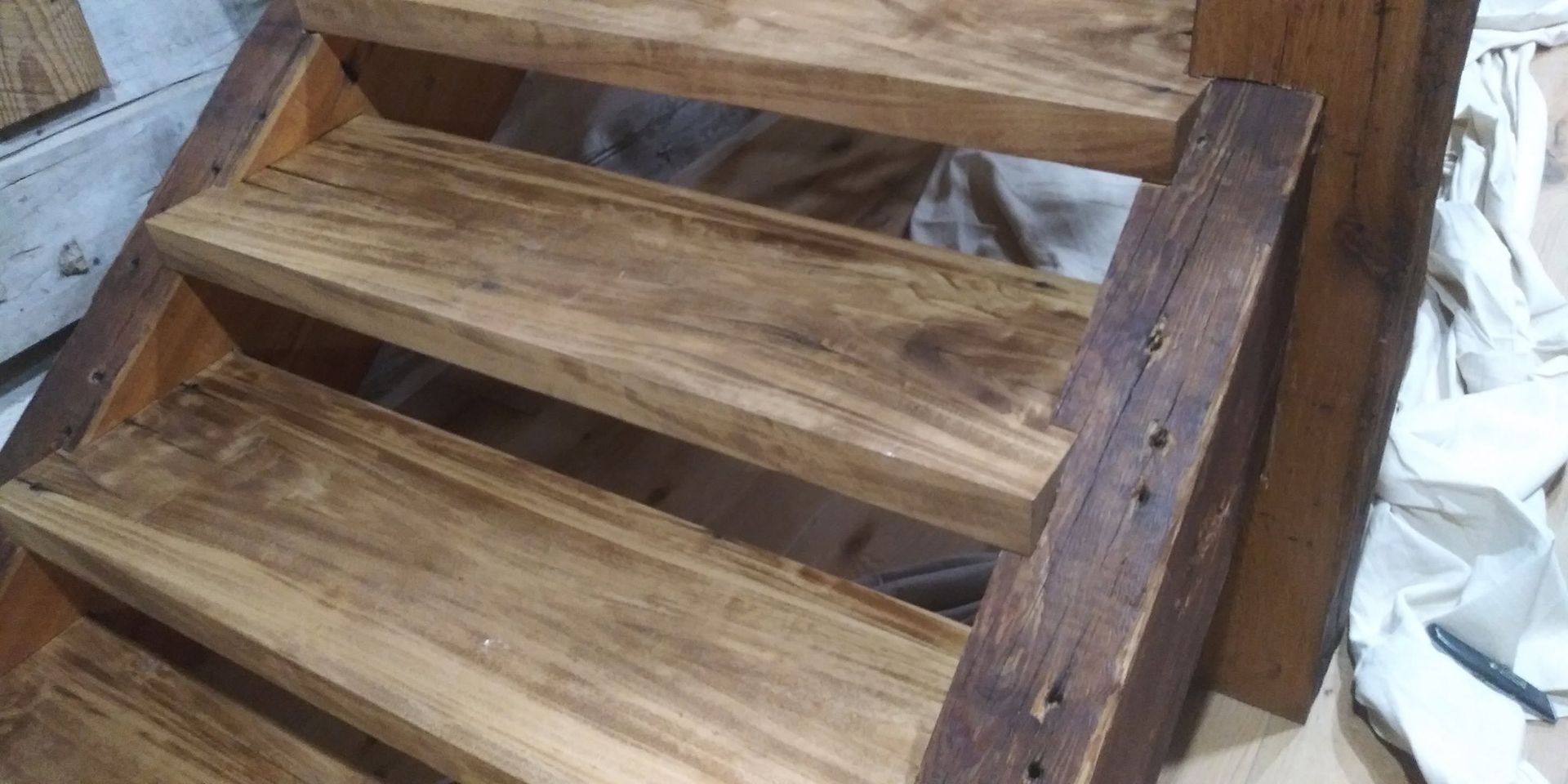 Wooden staircase with weathered brown steps and railings indoors