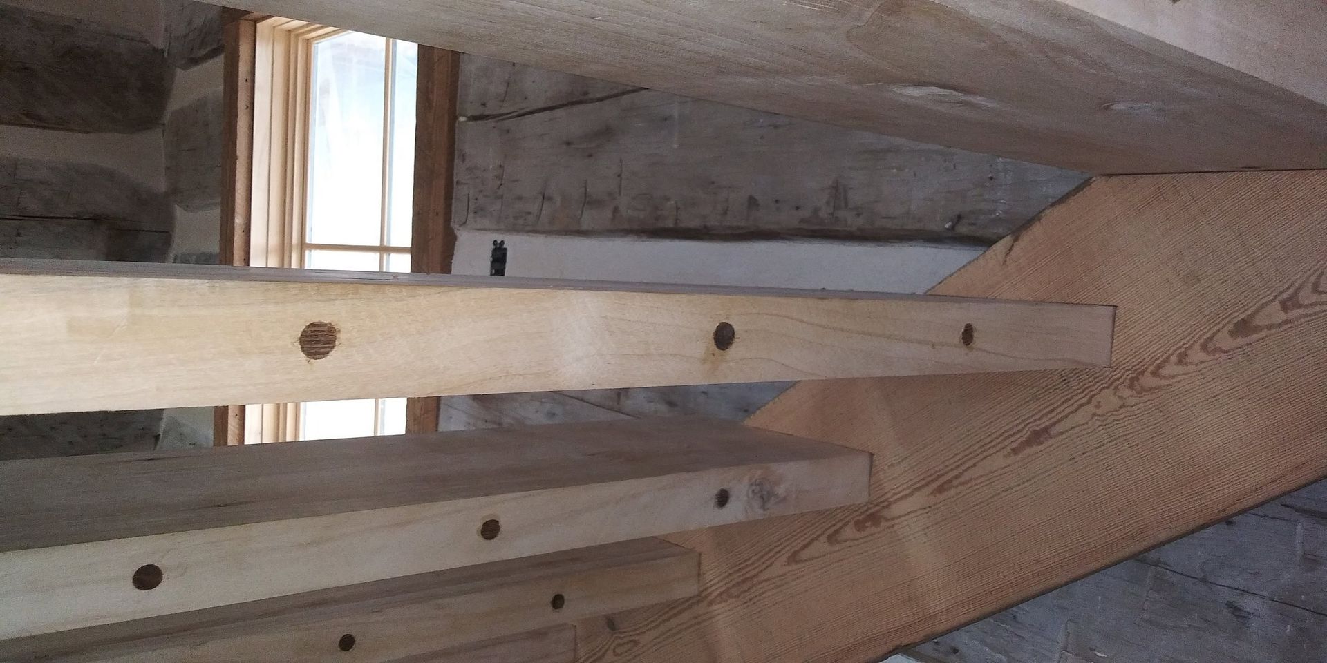 Wooden beams bolted to a concrete structure inside an unfinished building.