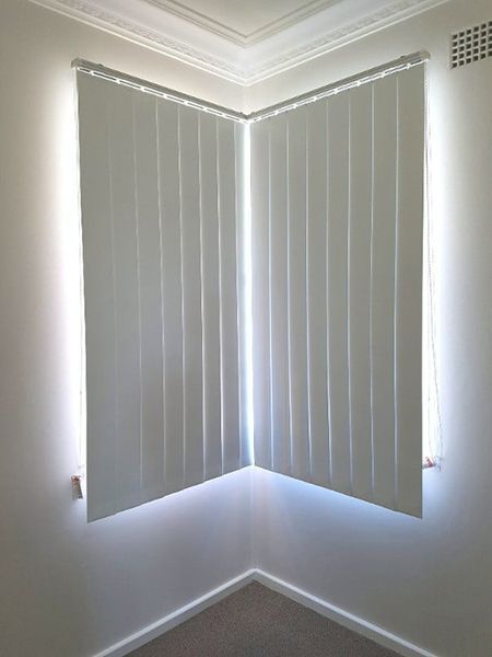 White Vertical Blinds Covering Corner Windows In A Room — Winning Blinds in Cardiff, NSW