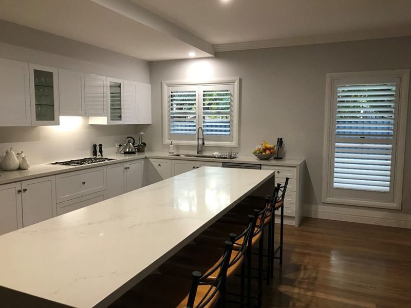 White Kitchen With Island, Countertops, And Cabinetry — Winning Blinds in Cardiff, NSW