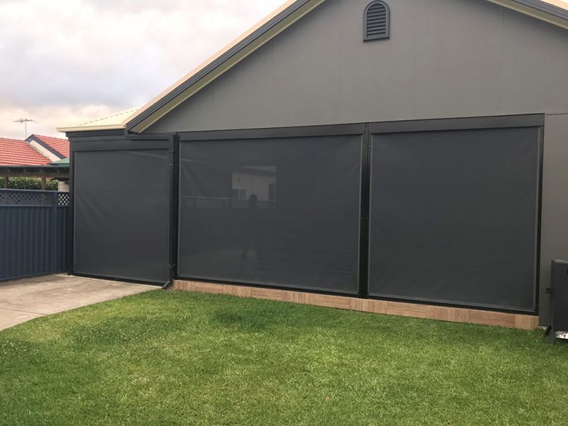 Exterior View Of A Building With Dark Gray Retractable Sun Shades — Winning Blinds in Cardiff, NSW