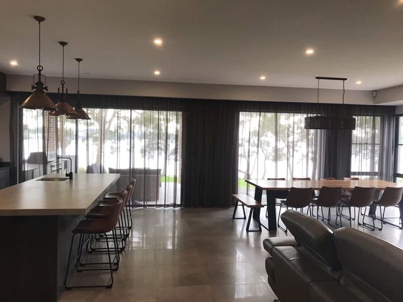 A Dining Room With Windows And Curtains, And A Kitchen Island — Winning Blinds in Cardiff, NSW