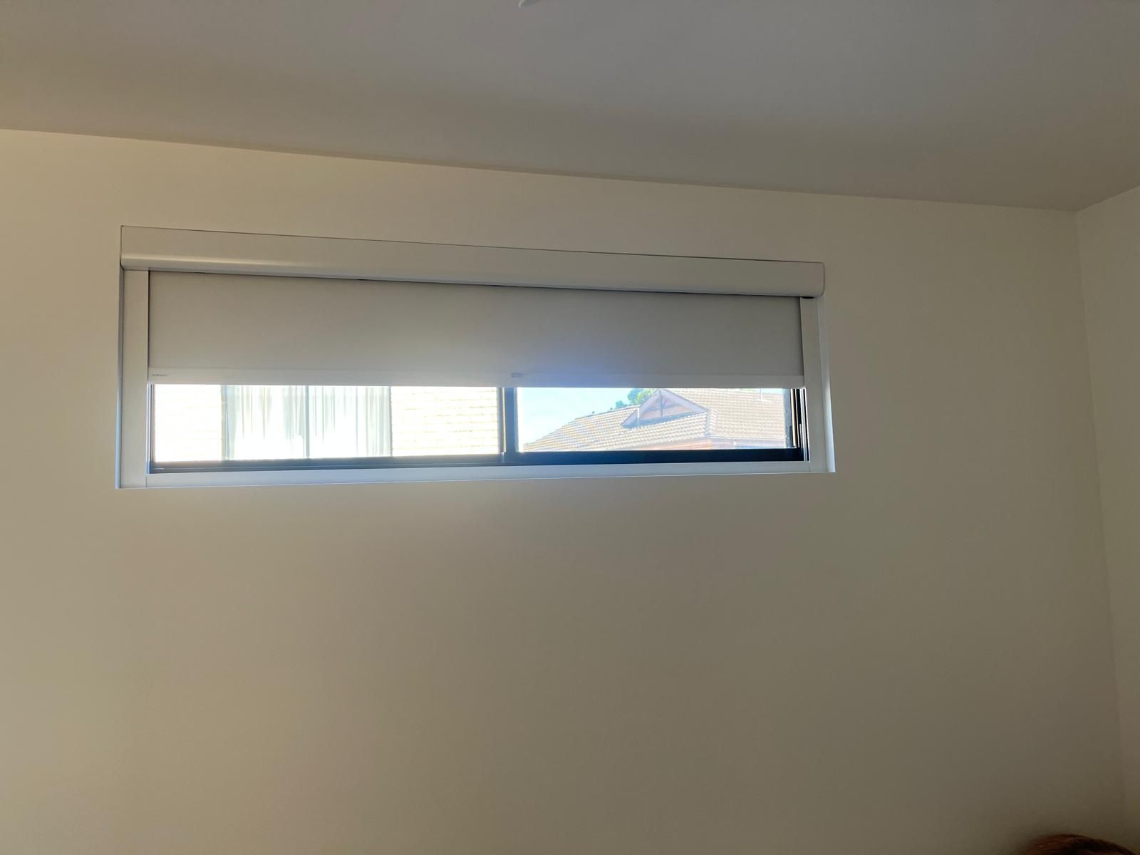 Small white room with a narrow horizontal window and partially closed blinds.