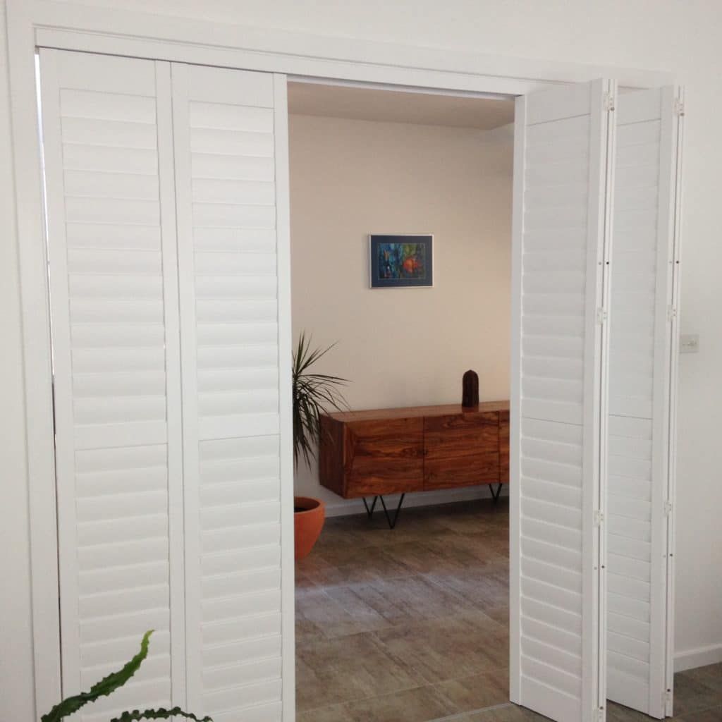 A Room with White Shutters and A Wooden Dresser — Winning Blinds in Beresfield, NSW