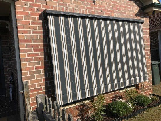 A Striped Awning, Black And White, Over A Window On A Brick Wall — Winning Blinds in Cardiff, NSW