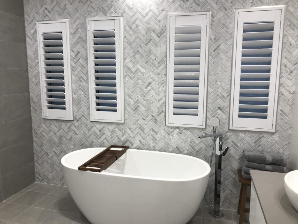 A Bathroom with A Bathtub and Shutters on The Wall — Winning Blinds in Cardiff, NSW