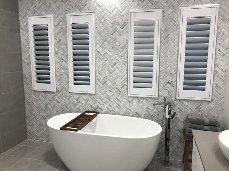 White Bathtub In Front Of Wall With Four White Shutters — Winning Blinds in Cardiff, NSW