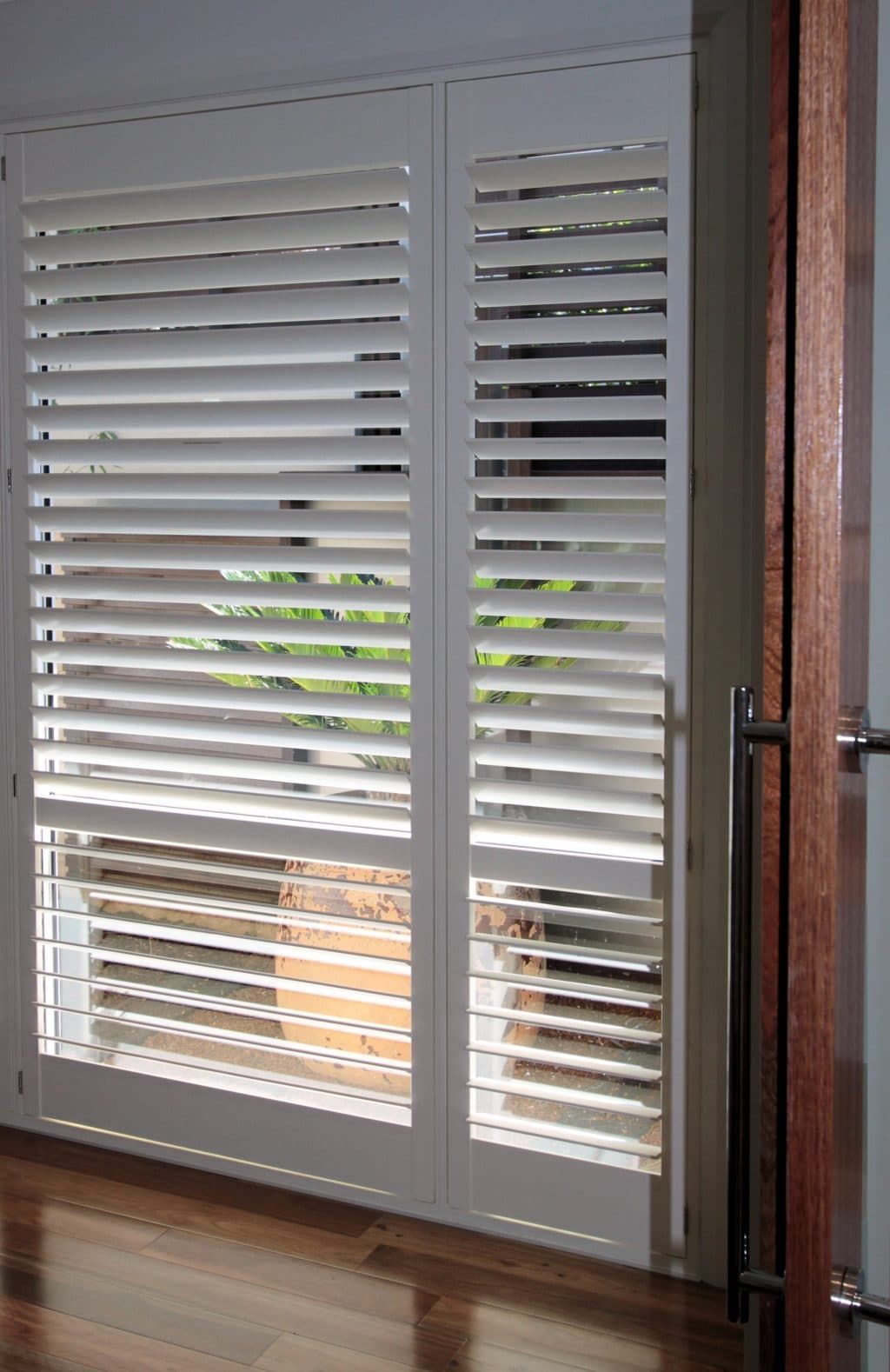 A Pair of White Shutters on A Window in A Room — Winning Blinds in Port Stephens, NSW