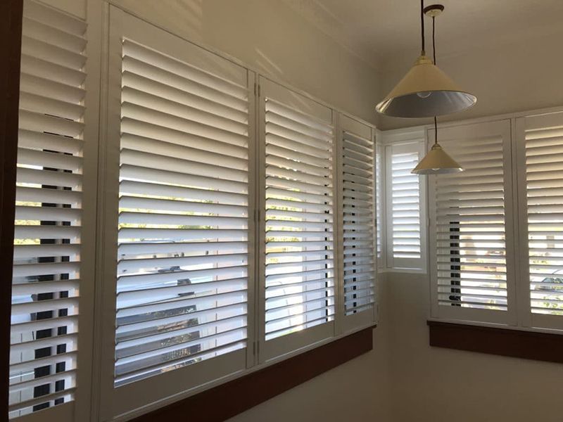 White Shuttered Windows In A Room With Two Pendant Lights — Winning Blinds in Cardiff, NSW
