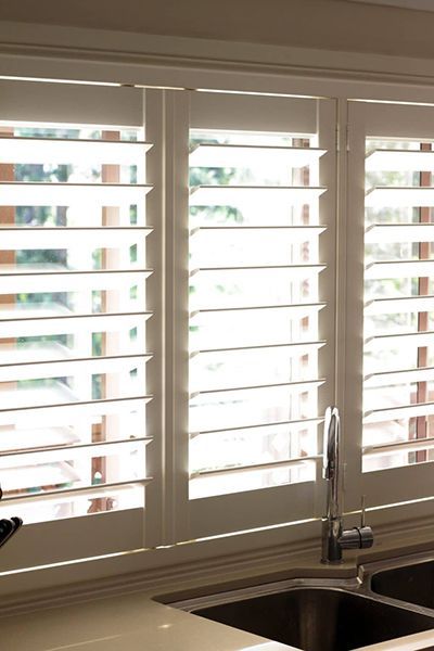 White Window Shutters Above A Kitchen Sink — Winning Blinds in Cardiff, NSW