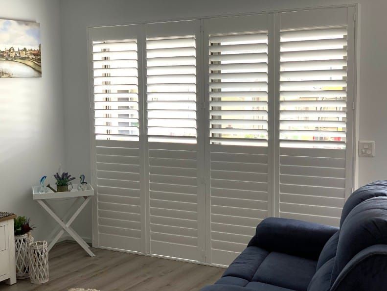 White Shutters On A Window In A Living Room — Winning Blinds in Cardiff, NSW