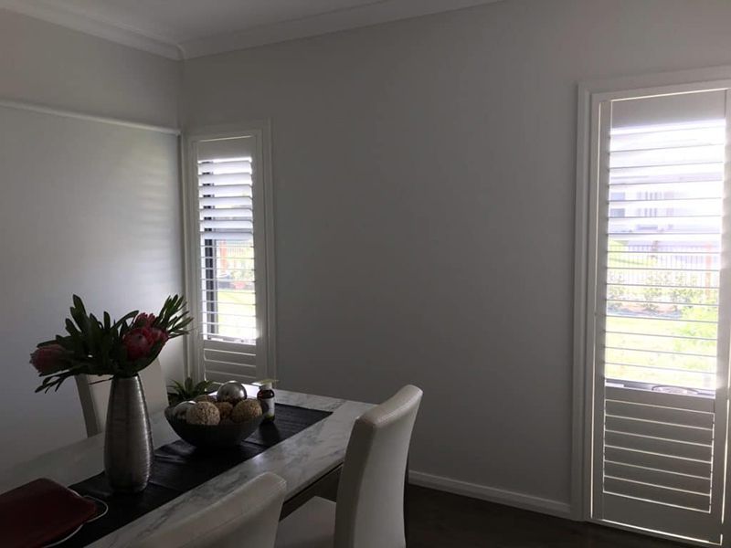 Dining Room With A Wooden Table, And Two Shuttered Windows — Winning Blinds in Cardiff, NSW