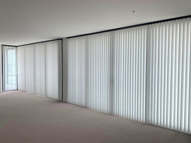 Large White Vertical Blinds Covering The Windows Of A Bright Room — Winning Blinds in Cardiff, NSW