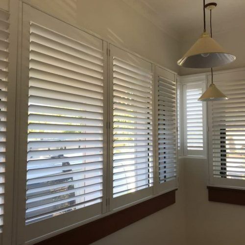 A Room With White Shutters on the Windows and Two Lamps Hanging From the Ceiling — Winning Blinds in Cardiff, NSW