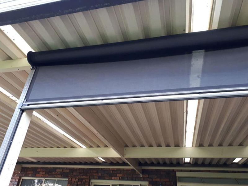 A Lowered Grey Outdoor Blind Attached To A Metal Roof — Winning Blinds in Cardiff, NSW