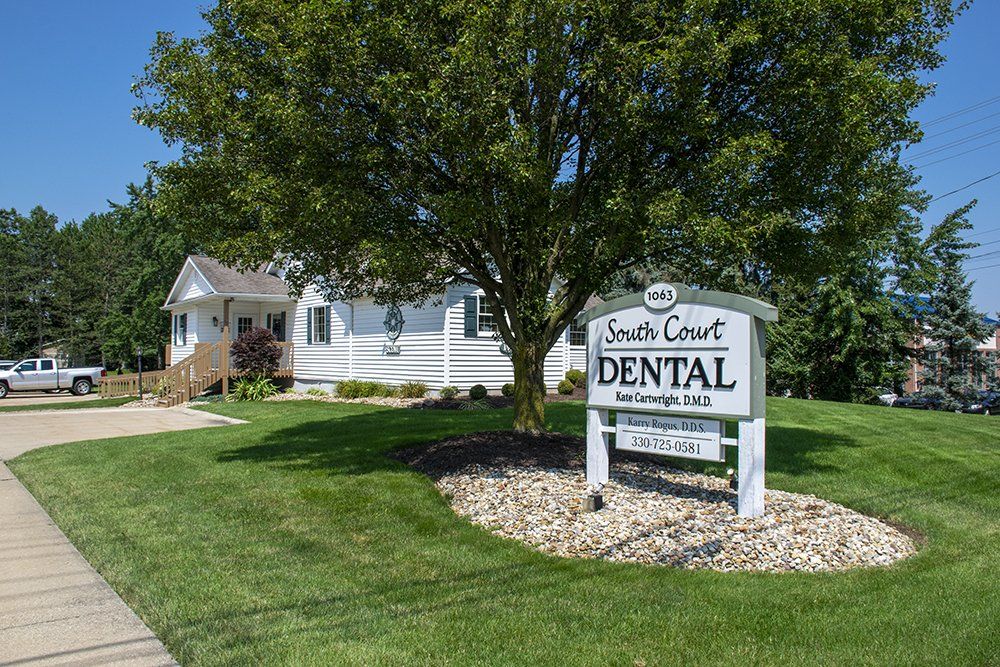 South Court Dental office with a sign, tree, and lawn.