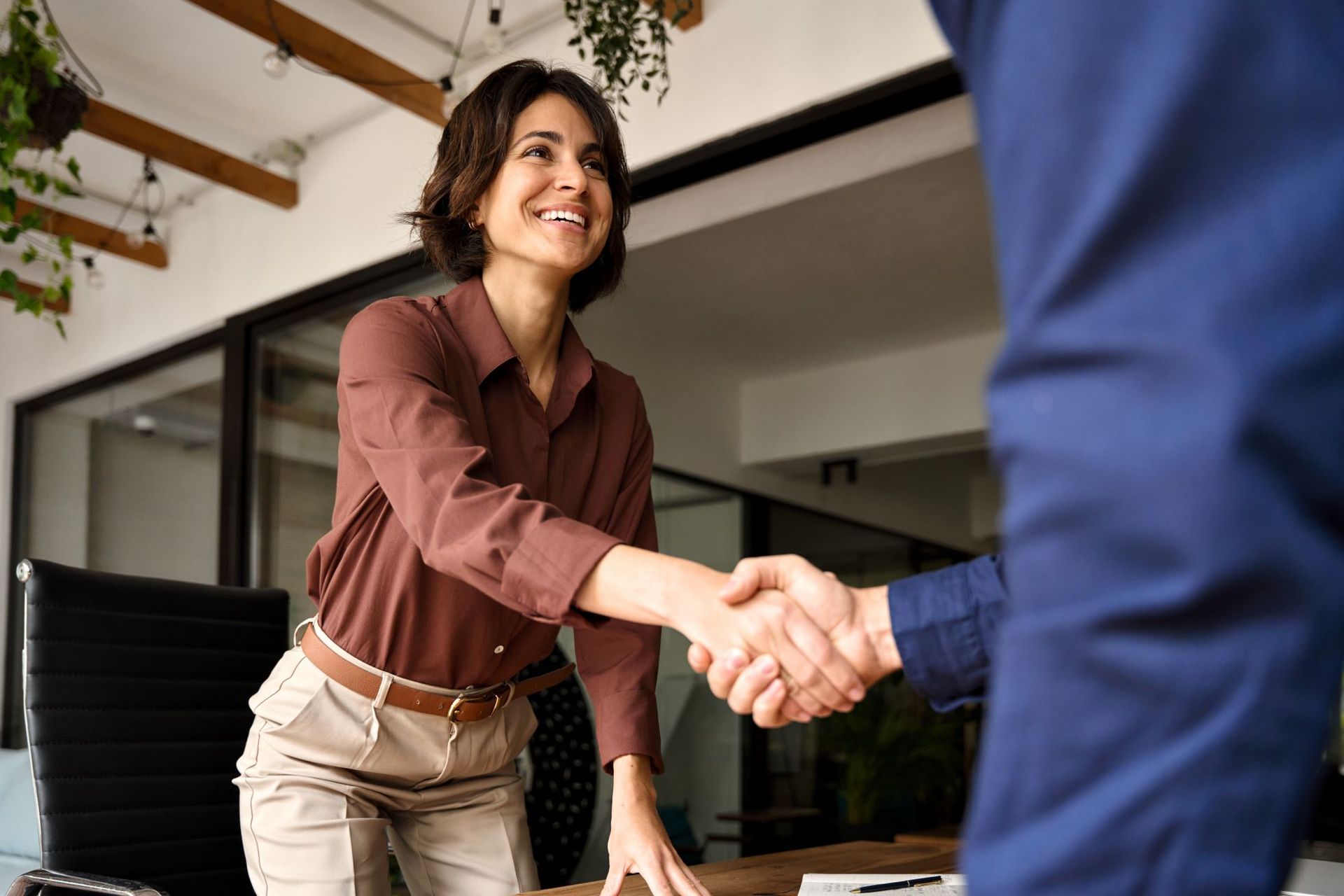 A woman is shaking hands with a man in an office.