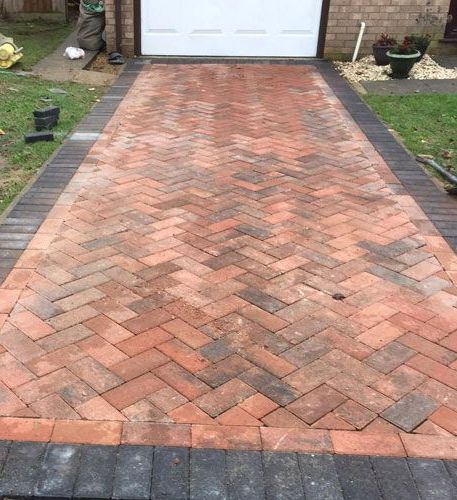 A brick driveway is being built in front of a garage door.