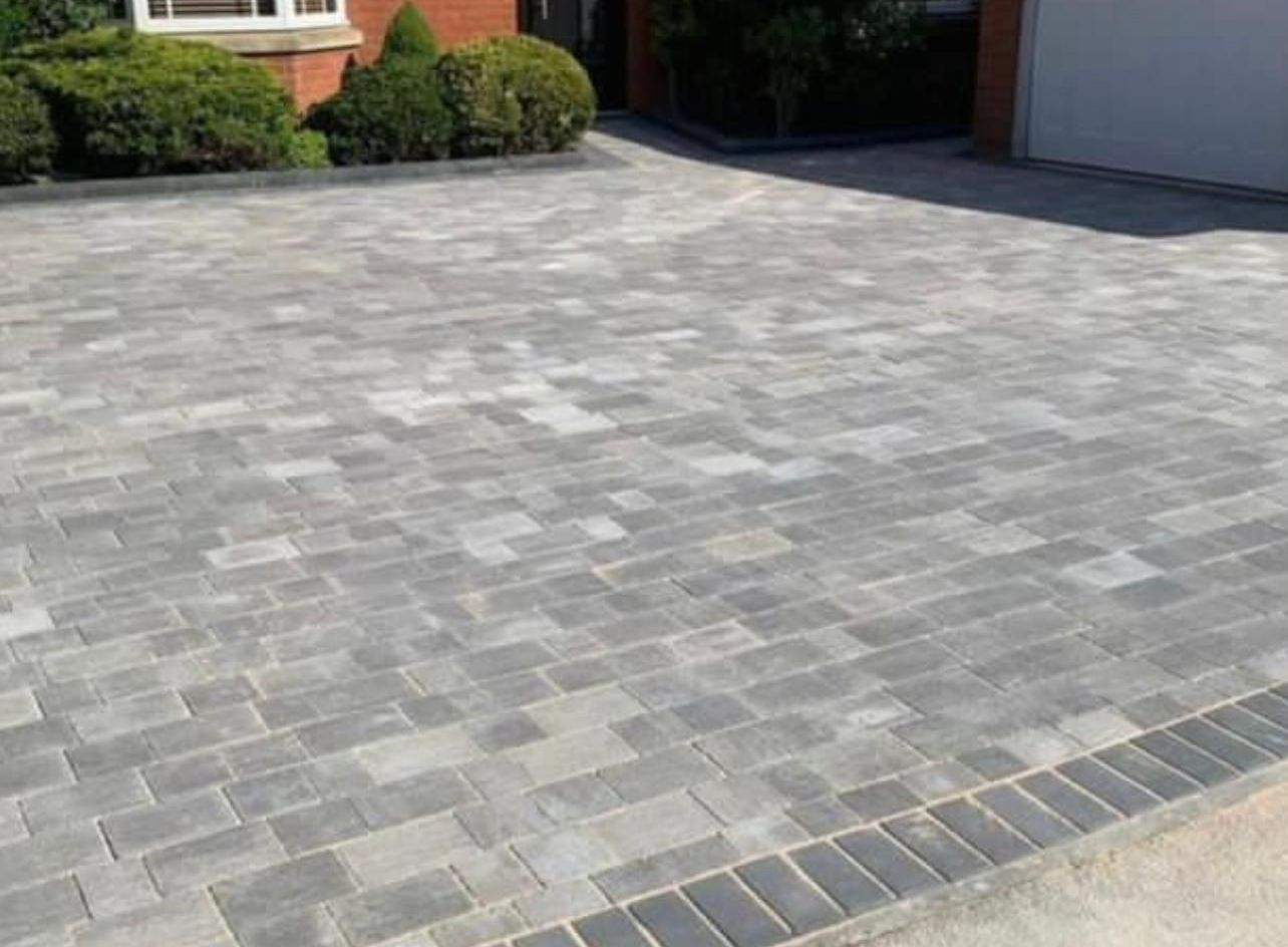 A brick driveway in front of a house with a garage.
