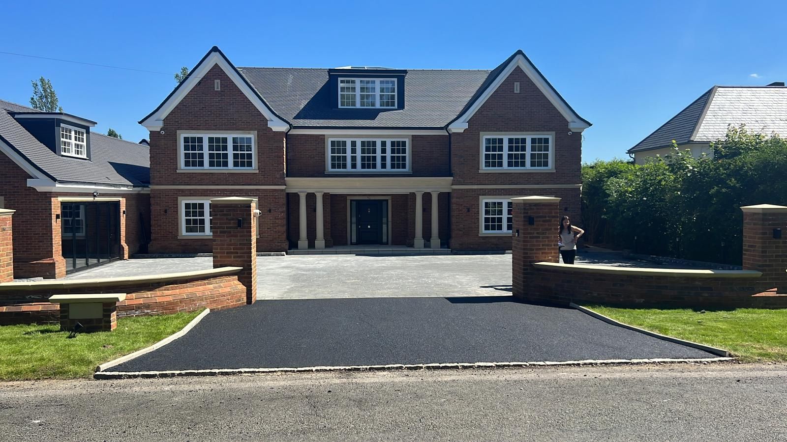 A large brick house with a black driveway in front of it