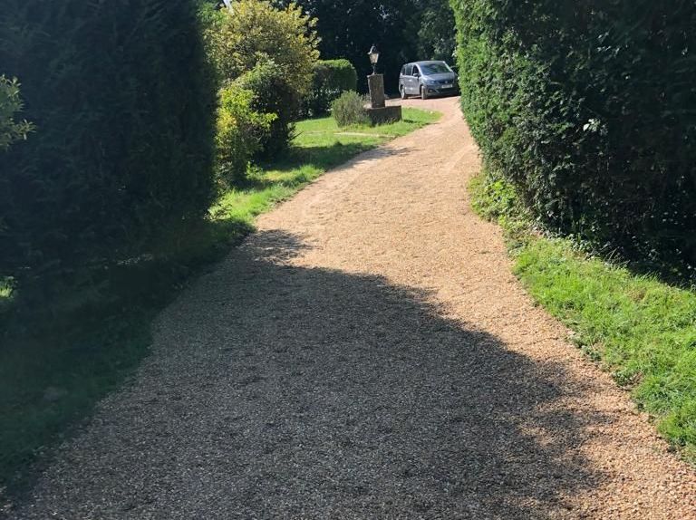 A car is parked on the side of a gravel road.