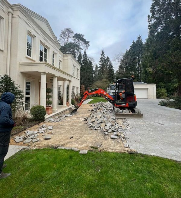 Woking driveway preparation by Surrey Hills. Mini digger on site, removing old paving for a new modern driveway installation.