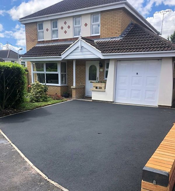 Newly laid black tarmac driveway for a Woking home, showcasing a clean finish by Surrey Hills Driveways.