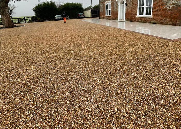Woking gravel driveway by Surrey Hills, leading to a brick house.