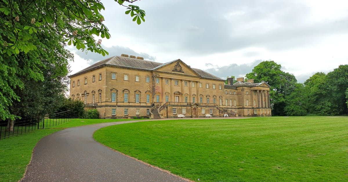 There is a large building in the middle of a park with a path leading to it.