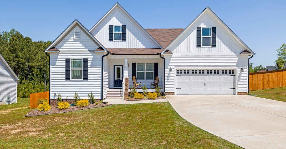 A white house with a garage and a driveway in front of it.